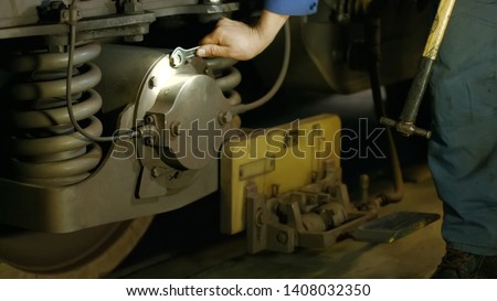 Mechanic repairing train at the depot. Wheel of subway train close up. Technical specialist tightening the screws.