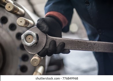 Mechanic repairman at the factory screws big bolt with large and heavy wrench key, holding it with both hands - Powered by Shutterstock