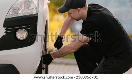 Mechanic Repairs Car, Working Diligently To Unscrew Wheel Bolt With Wrench