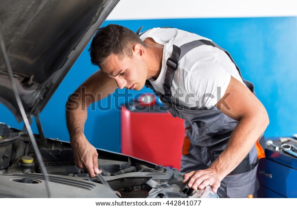 Mechanic repairs car in\
workshop