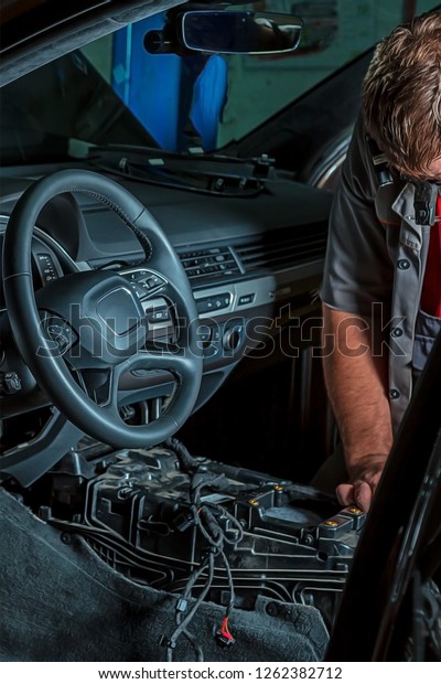 A mechanic repairs\
a luxury SUV Repair wiring, gearboxes, disassembled interior\
premium crossover. Removed chairs. Leather interior. Neat repair\
service center.