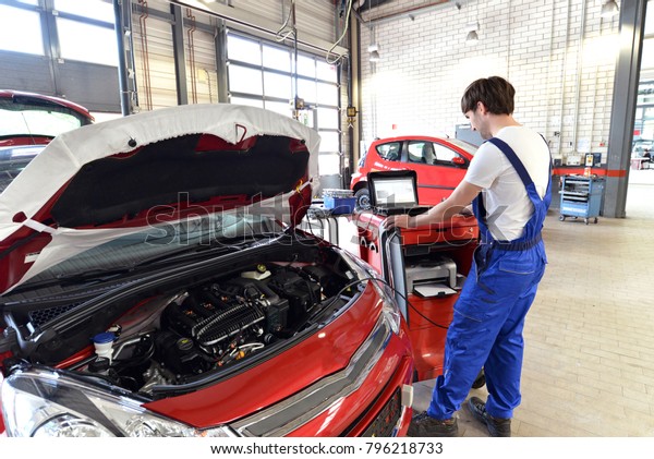 mechanic repairs motor from an automobile with\
the help of a diagnostic\
computer