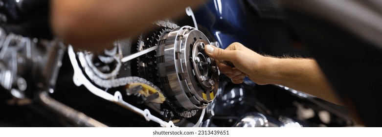 Mechanic repairs motor and chain of motorcycle in workshop - Powered by Shutterstock