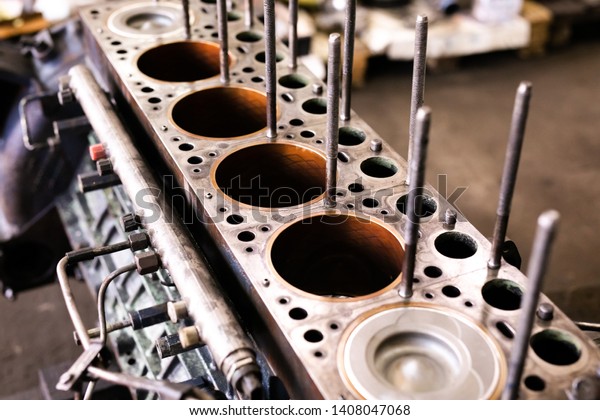 Mechanic repairs old motor of truck in a car\
repair station. Disassemble engine block vehicle. Motor capital\
repair. Car service\
concept.