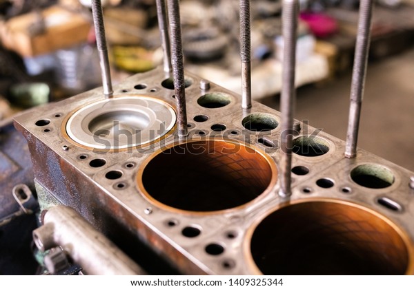 Mechanic repairs old motor of truck in a car\
repair station. Disassemble engine block vehicle. Motor capital\
repair. Car service\
concept.