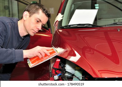 Mechanic repairs a red bonnet.