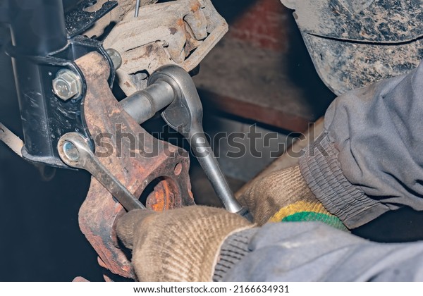 Mechanic repairs the\
running gear of a car car. Hands of a mechanic close-up. Small\
business concept.