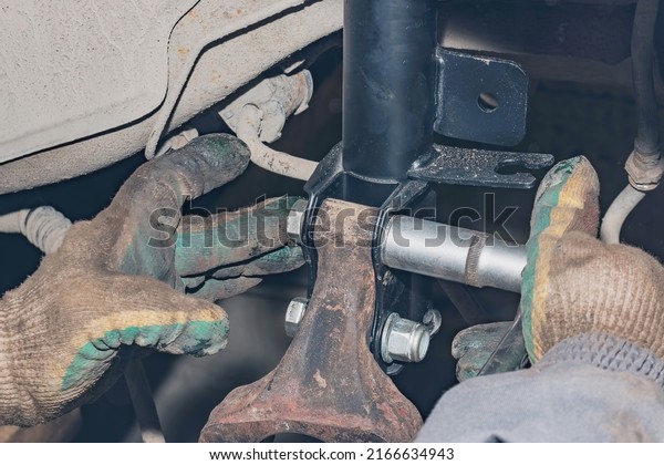 Mechanic repairs the\
running gear of a car car. Hands of a mechanic close-up. Small\
business concept.