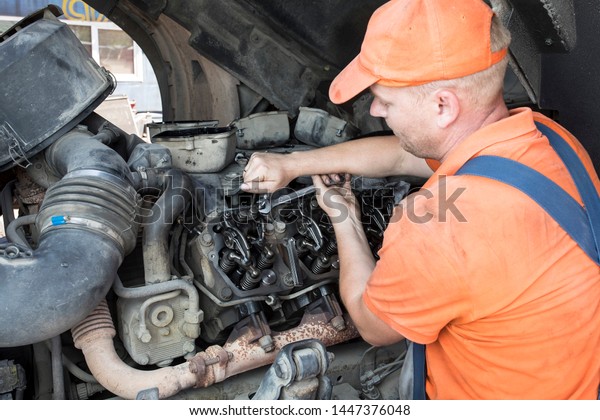 Mechanic repairs a truck. \
adjustment of valves of the diesel motor.  Replacement\
nozzles.