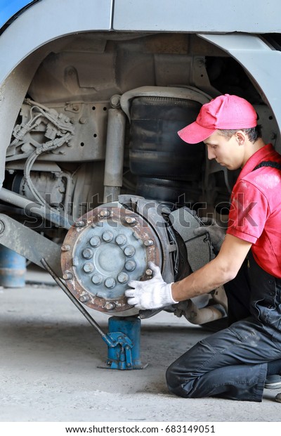 A\
mechanic repairs a truck. Replace brake disc and\
pads