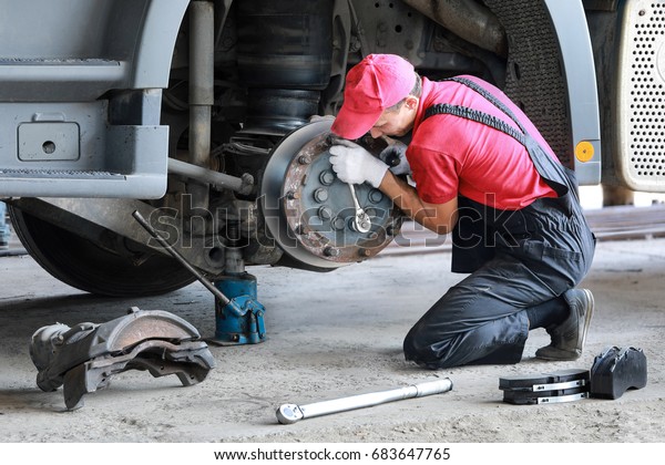 A\
mechanic repairs a truck. Replace brake disc and\
pads