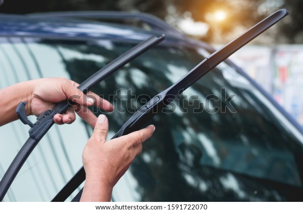 Mechanic replace windshield wipers on car.\
Replacing wiper blades\
Change cars wiper blades. Technician Man\
changing windshield wipers blades on\
car.