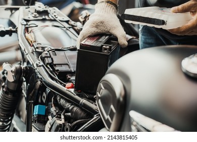  mechanic replaces motorcycle battery and holding Acid pack or sealed battery electrolyte pack to prepare for fill up battery, motorcycle maintenance and service and repair concept . selective focus