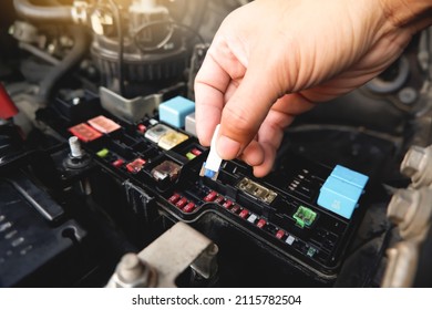 Mechanic replaces the spare fuse to the car fuse box with the fuse clip tool