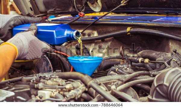 mechanic replacing new oil engine and pouring to car\
in service shop