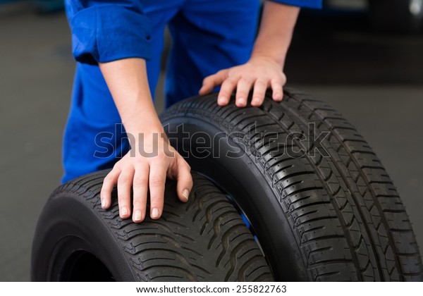 Mechanic\
rolling a tire wheel at the repair\
garage