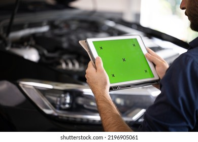 Mechanic Running Diagnostics Software On Tablet Computer With Green Screen Mockup Chromakey. Unrecognizable Vehicle Service Manager Worker Check And Maintenance To Repair The Engine Car In Workshop.