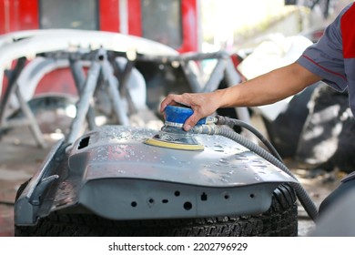 A mechanic with a sander is polishing the parts of the car. - Powered by Shutterstock