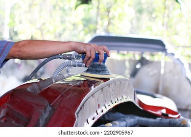 A mechanic with a sander is polishing the parts of the car to paint the body of the car. - Powered by Shutterstock