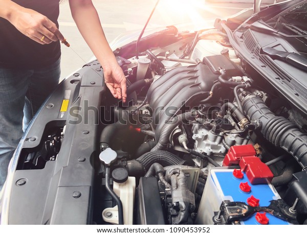 Mechanic with scan tool diagnosing car in open\
hood with sunshine morning . Checking level motor oil in a car\
before driving to\
travel.