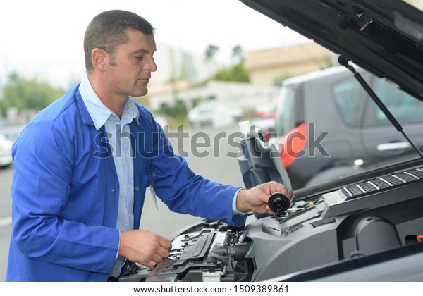 mechanic with\
scan tool diagnosing car in open\
hood