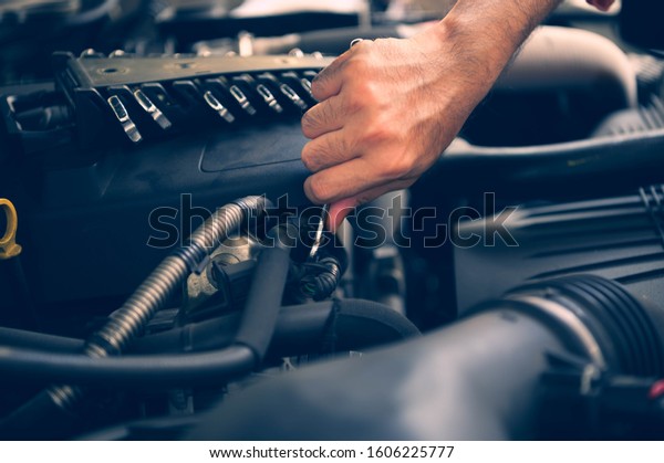 Mechanic with\
scan tool diagnosing car in open\
hood