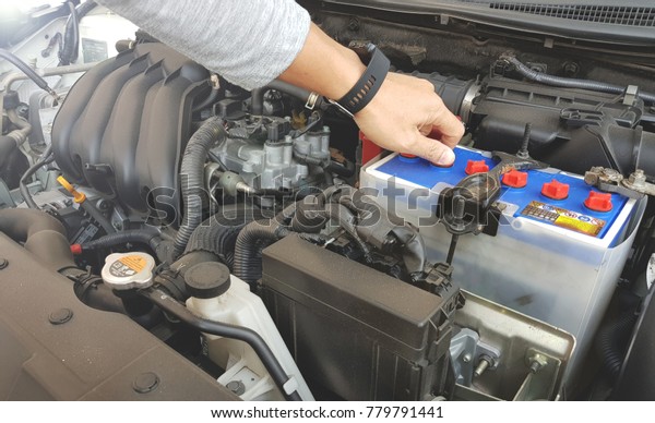 Mechanic with scan tool diagnosing car in open\
hood. A man checking car battery  and car engine before driving to\
travel, Soft focus