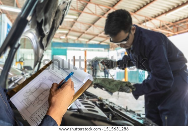 A\
mechanic service car in garage is check a list car and Asian man\
auto mechanic using a wrench to service car in\
garage.