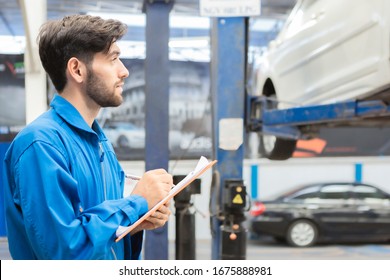 A mechanic service car in garage is paper checklist car. service car, repair, maintenance concept.Technician doing the checklist for repair machine a car in the garage.