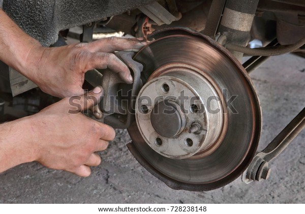 Mechanic servicing disc\
brakes of car