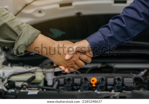 The mechanic shaking hands with customer after\
finish checking car system.Professional service.checking the opened\
hood car.Repair service.