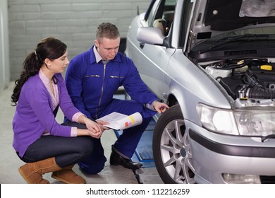 Mechanic showing the car wheel to a client in a garage - Powered by Shutterstock