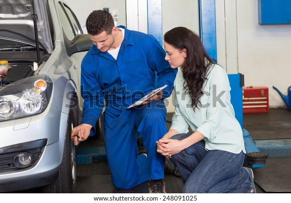 Mechanic showing customer the problem with car at\
the repair garage