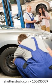 Mechanic Showing  Paperwork To Car Owner In Garage