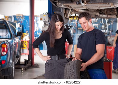 A mechanic showing the tread of a tire to a female customer - Powered by Shutterstock