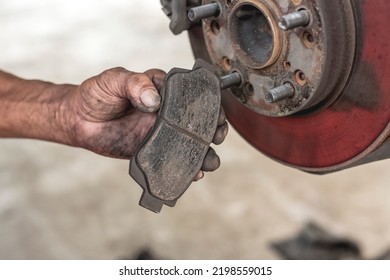 A Mechanic Showing Worn Disc Brake Pads Removed From A Car. Servicing And Replacing Old Parts Of A Vehicles At An Auto Repair Shop.