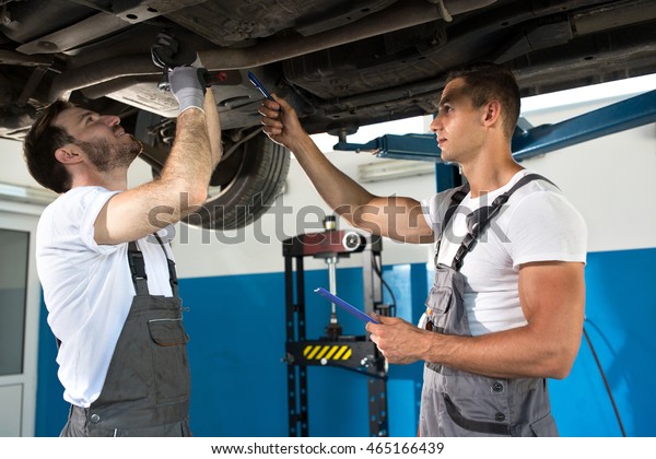Mechanic shows defect and problems with car,\
teamwork repair at\
service