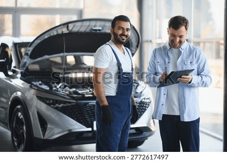 Mechanic and smiling customer completing paperwork for automotive repair and maintenance at a modern garage workshop