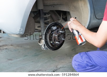 mechanic spray chemical to clean brake during tyre replacement service