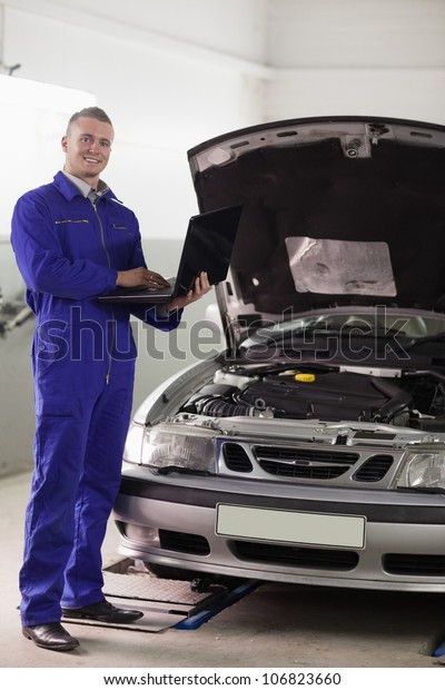 Mechanic\
standing while holding a computer in a\
garage