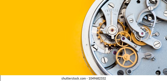 Mechanic stopwatch chronometer mechanism, spring bronze cogs wheels macro view. Shallow depth of field, selective focus. Yellow colorful background. Copy space. - Powered by Shutterstock