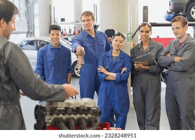 Mechanic and students discussing car engine in auto repair shop - Powered by Shutterstock