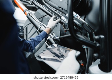 Mechanic with tablet computer control and fix problem of hydraulic hoses from industrial mining truck.
