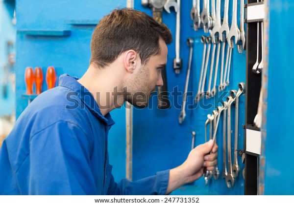 Mechanic\
taking a tool from wall at the repair\
garage