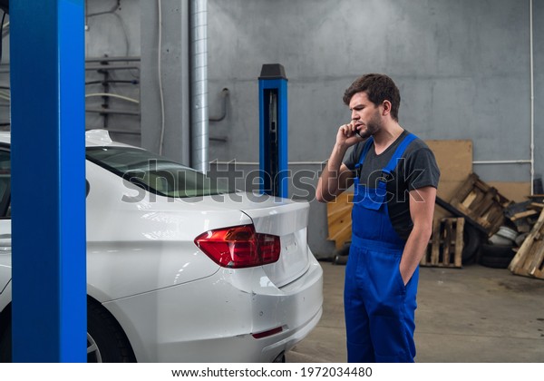 Mechanic\
talking on the phone and looking at the\
car