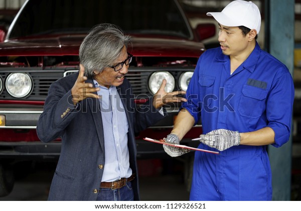 mechanic\
talking with unhappy  customer going through the maintenance\
checklist .  Car mechanic helps a customer standing next to the\
serviced car and looking through  clipboard\
.
