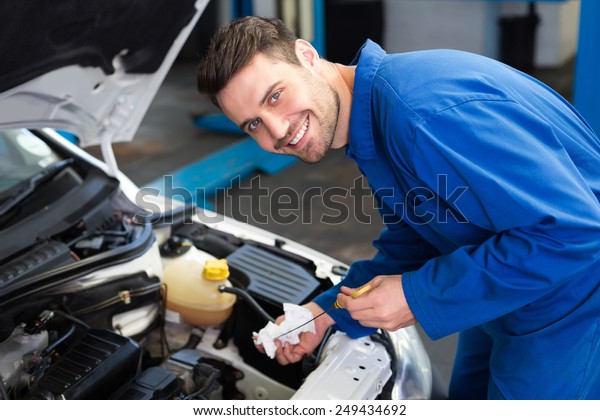 Mechanic testing\
oil in car at the repair\
garage