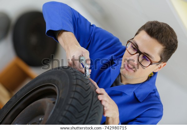 mechanic with tool\
changing tyre of car