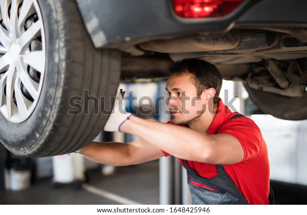 mechanic with tool checking\
the car