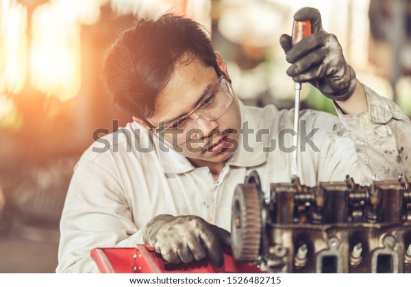 Mechanic with a tool in his hands repairing the motor of\
the machine. 